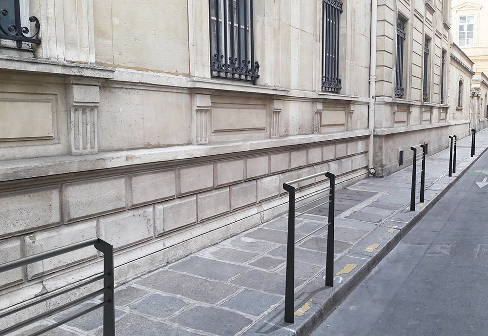 Cinq barrières TUB grises incrustées en bordure de trottoir dans une photographie