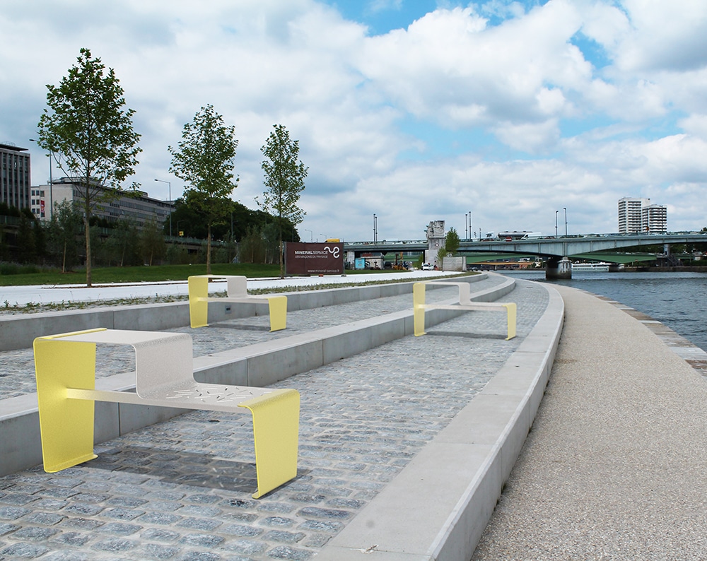 Trois tables gigogne LUD jaunes incrustées sur des pavés en pierre, près d'un fleuve